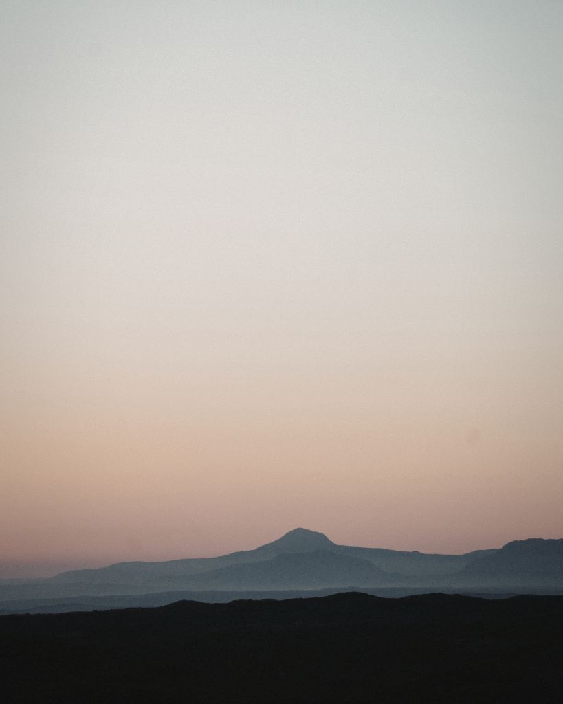 Distant hills layered beneath a soft, fading sky, creating a sense of calm and space.