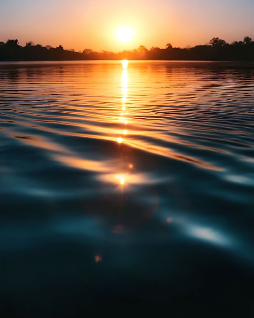 Calm water reflecting the warm colors of the setting sun in quiet stillness.