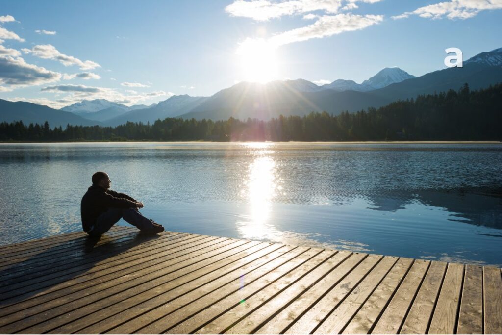 The life we keep postponing: person reflecting beside a window with an open notebook