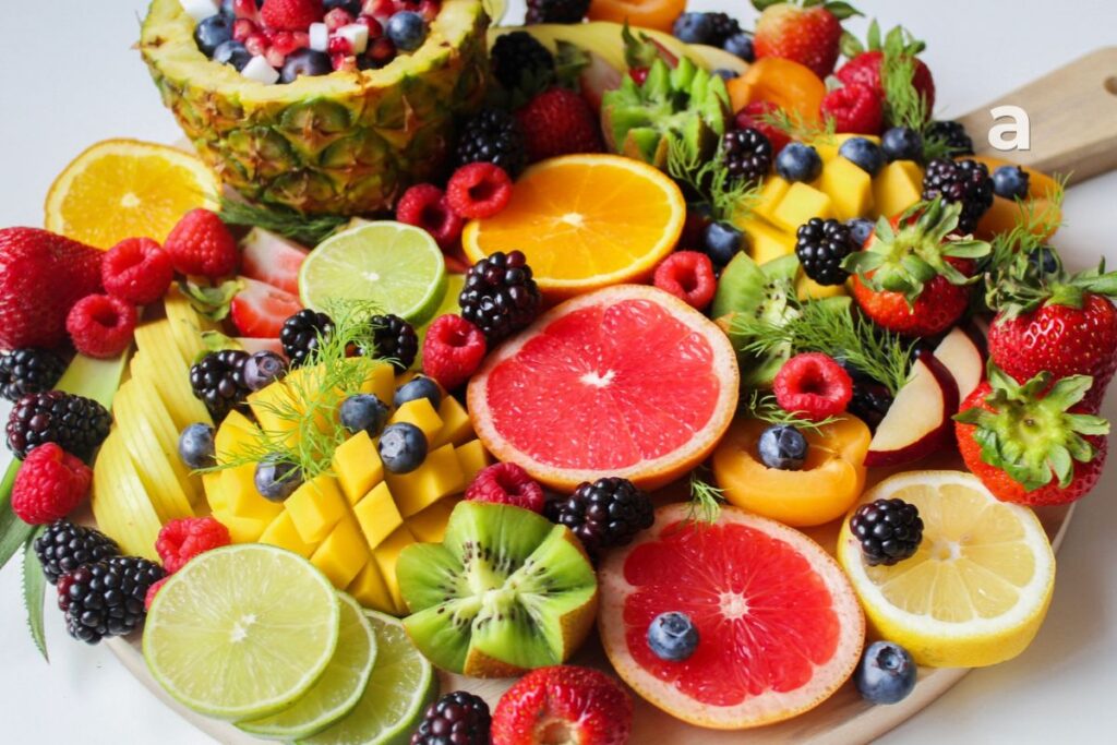 Vitamin C-rich foods including guava, amla, oranges, kiwi, strawberries, bell peppers, broccoli, tomatoes, papaya, and lemon.